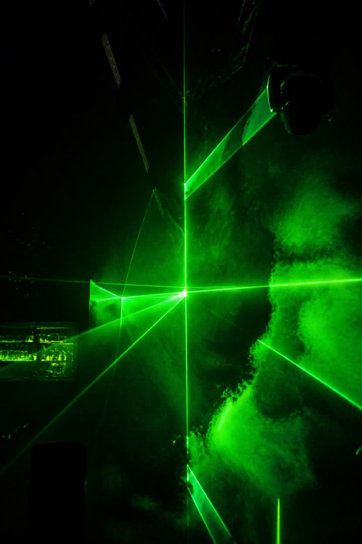 Acid-green lasers cutting through smoke in a dark club